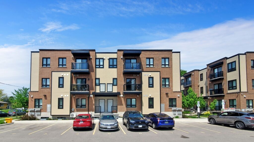 Apartment complex with a parking lot featuring two parked cars in front.