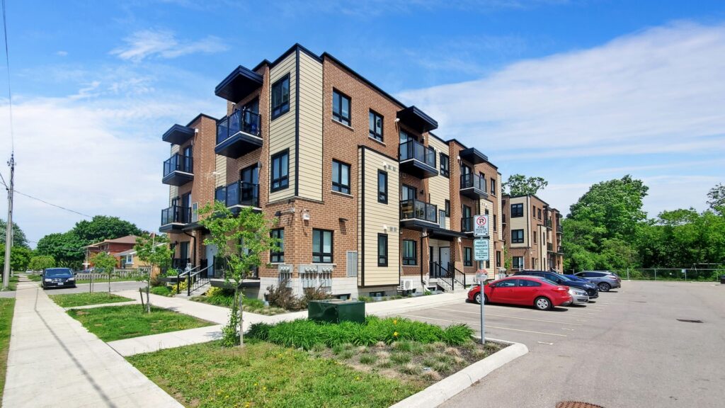 Apartment complex with multiple cars parked in front, showcasing a residential area.