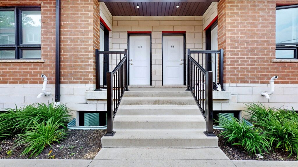 A front door with a railing and steps leading up to it, surrounded by a welcoming entrance.