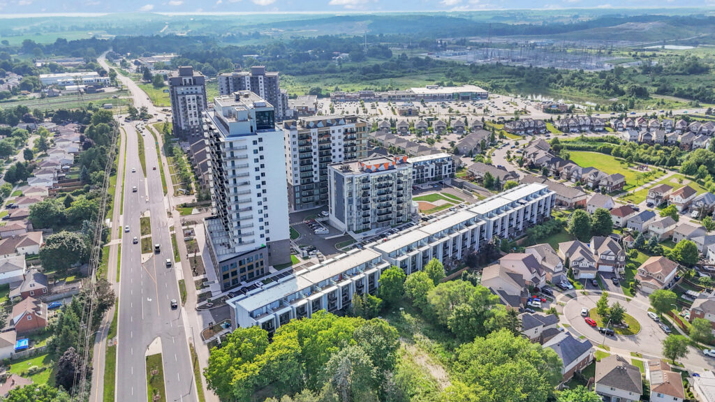 Aerial view of a residential area featuring houses, trees, and a highway running through the landscape.
