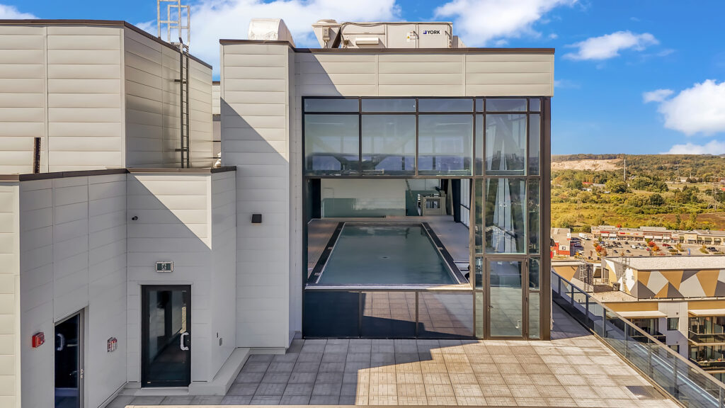 A modern apartment building featuring a rooftop swimming pool with lounge chairs and city views.