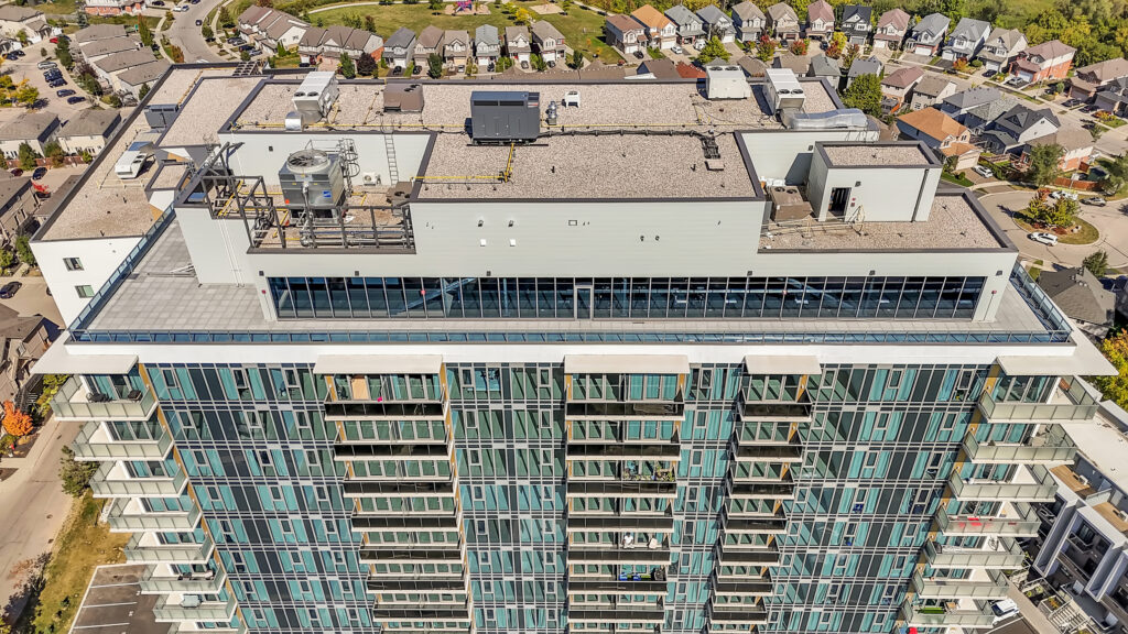 Aerial view of a tall apartment building surrounded by green trees and city streets.