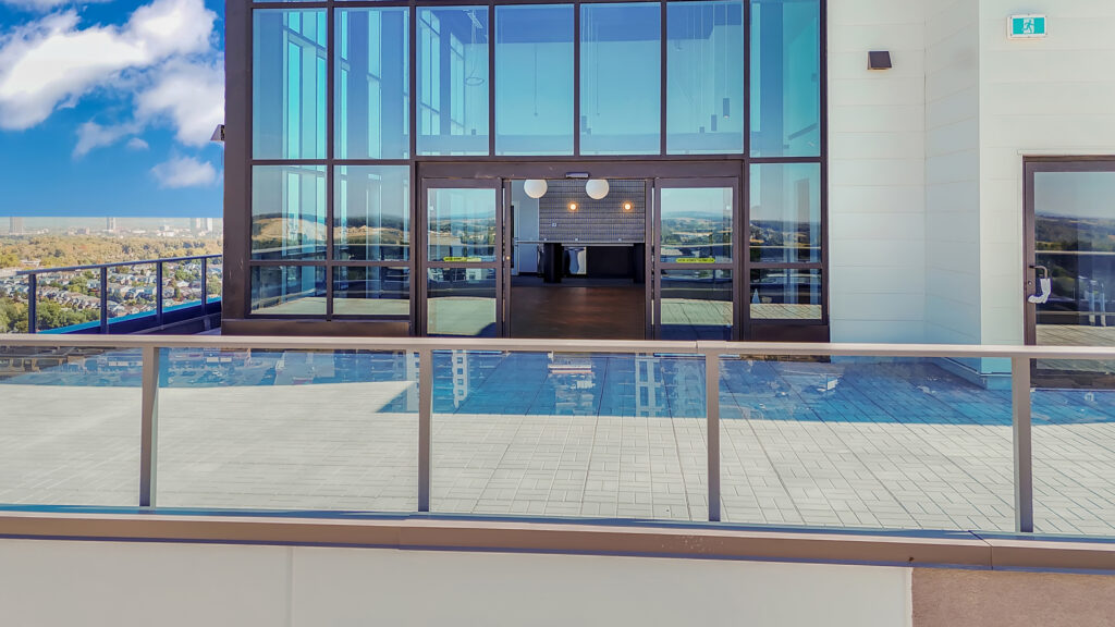 A balcony overlooking a vibrant city skyline with buildings and a clear blue sky.