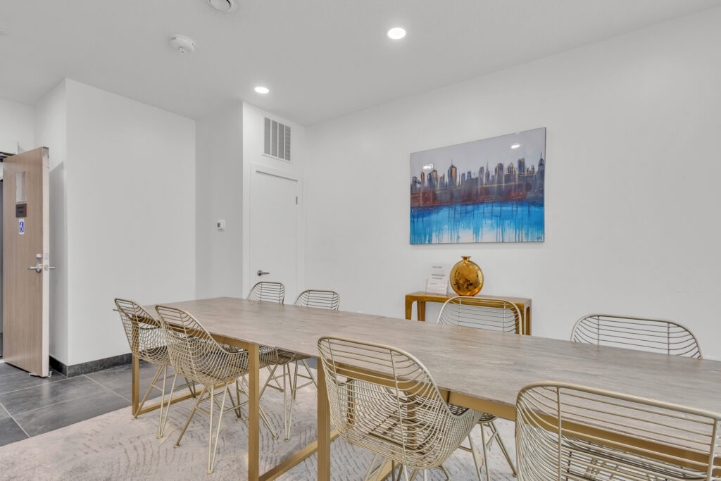 A dining room featuring a wooden table surrounded by four chairs, with soft lighting and a cozy atmosphere.