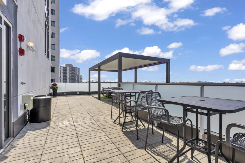 A balcony featuring several tables and chairs arranged for outdoor seating.