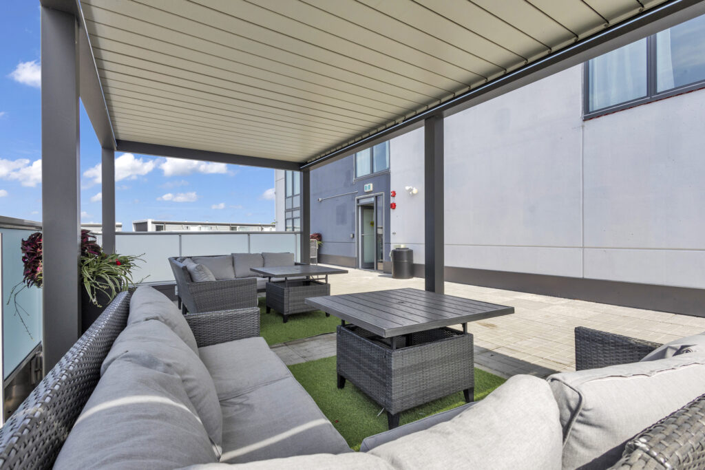 Rooftop patio featuring comfortable couches and tables for outdoor relaxation.