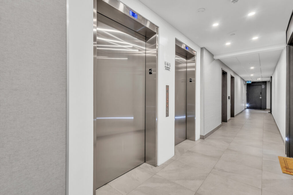 A long hallway featuring two elevators on opposite sides.