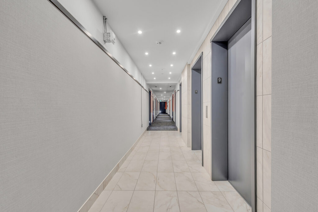 A hallway featuring white walls and gray tile flooring, creating a clean and modern look.