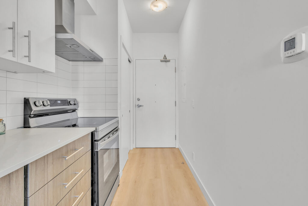 A bright kitchen featuring white cabinets and a modern stove top oven.