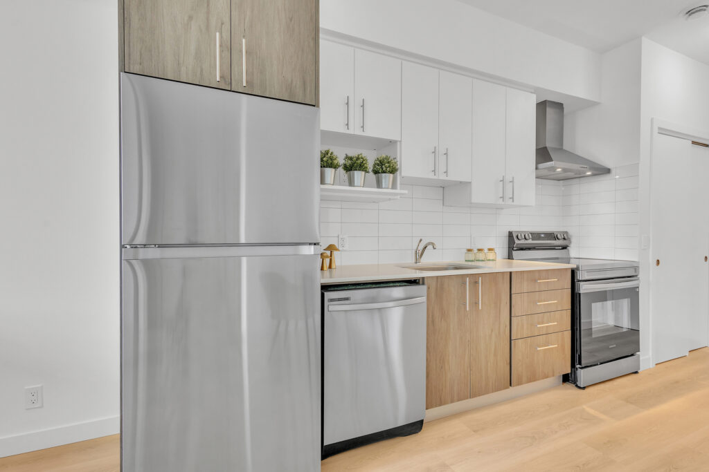 A modern kitchen featuring stainless steel appliances and warm wooden floors.