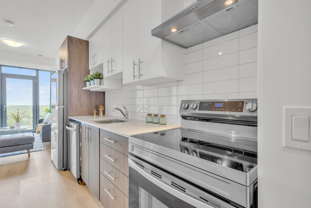 Modern kitchen with stainless steel appliances and a large window showcasing a city skyline.
