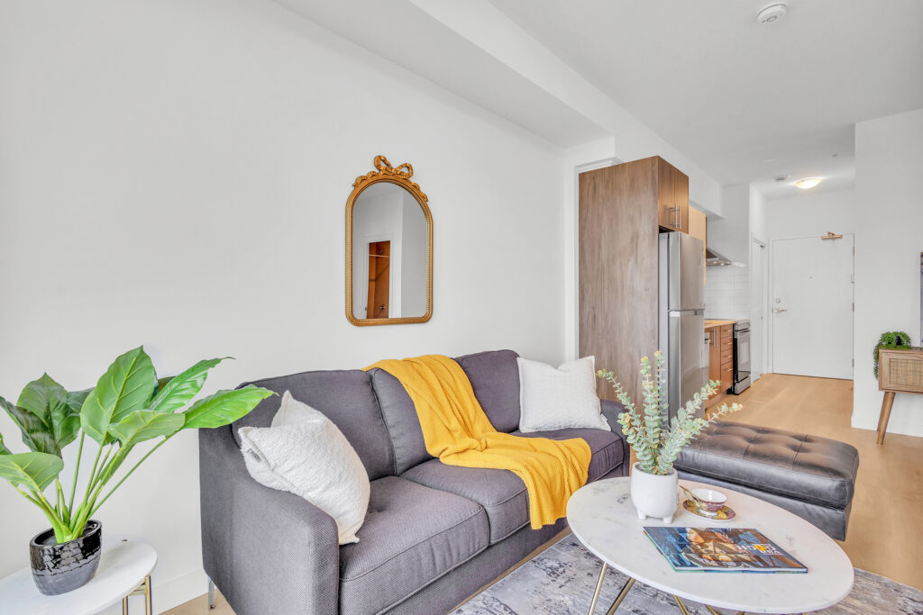 A cozy living room featuring a couch, coffee table, and a large mirror on the wall.