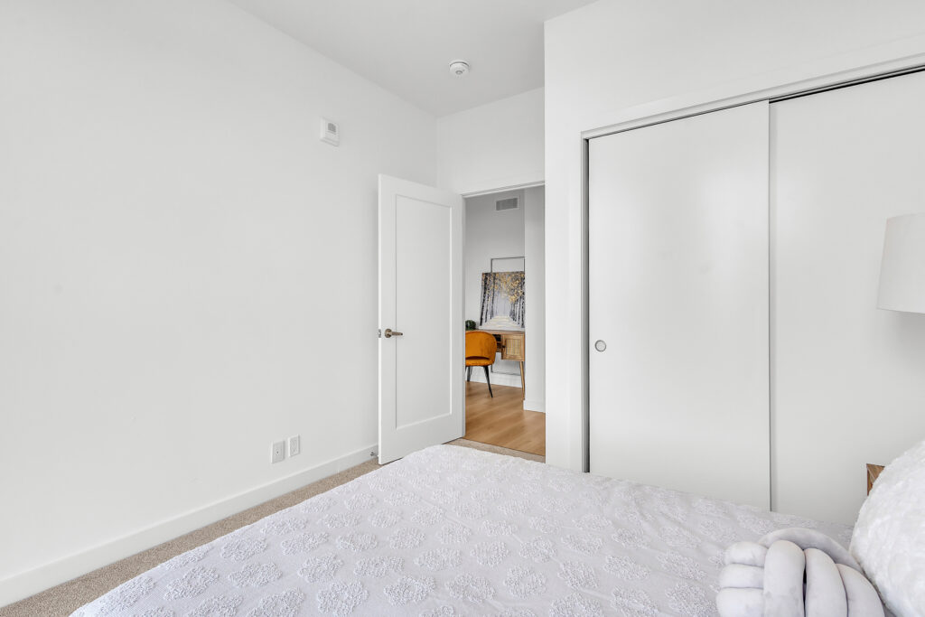 A cozy bedroom featuring white walls and a neatly made bed with soft bedding.
