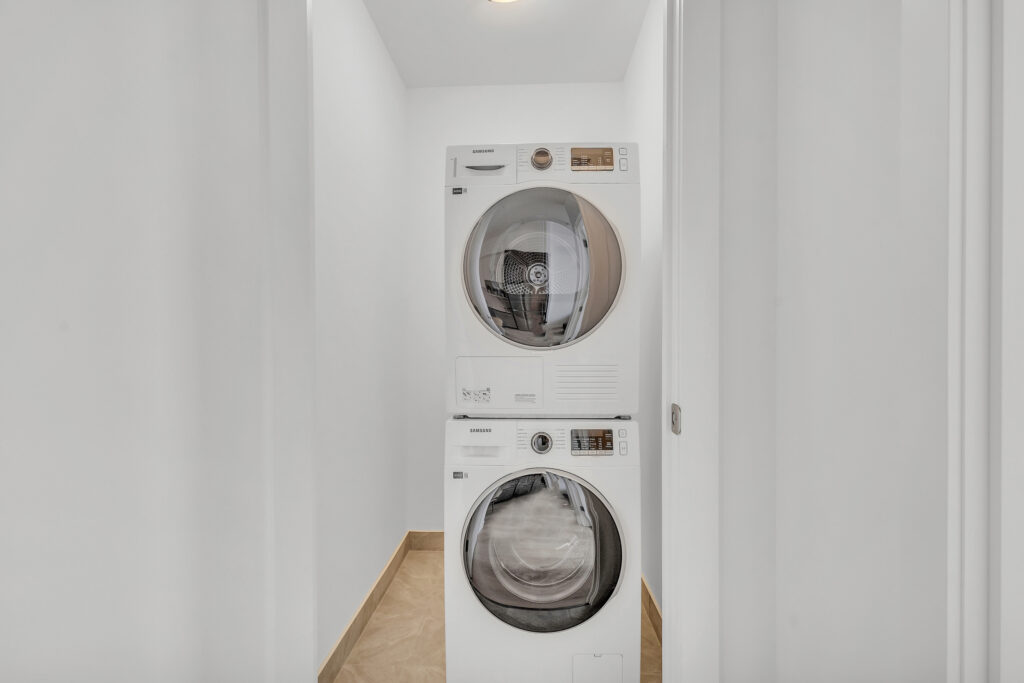 A white washer and dryer are placed side by side in a narrow hallway.