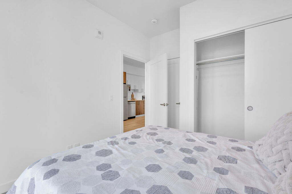 A cozy bedroom featuring a white bed against a plain white wall.