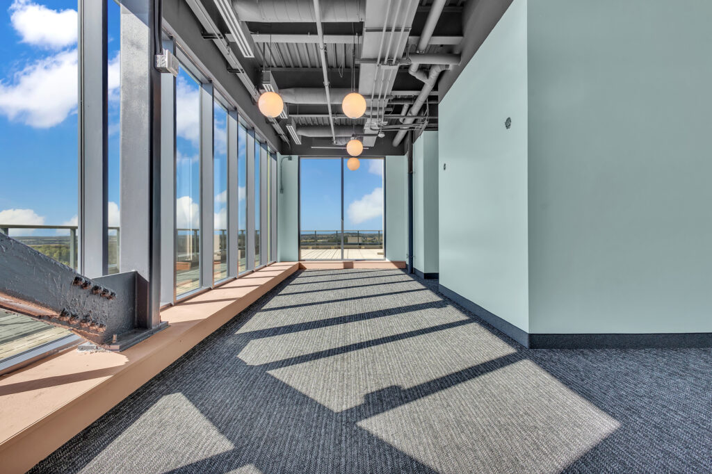 A long hallway featuring large windows and a soft carpeted floor.