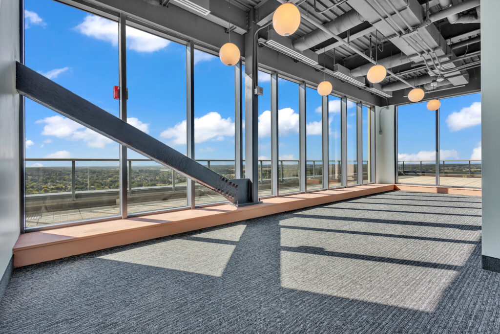 A spacious room with large windows offering a view of the city skyline.