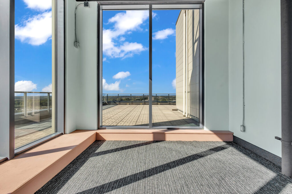 A spacious room with large windows showcasing a clear view of the blue sky.