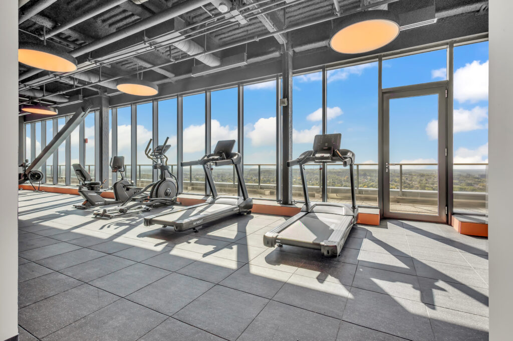 A gym featuring treadmills and large windows with a view of the city skyline.