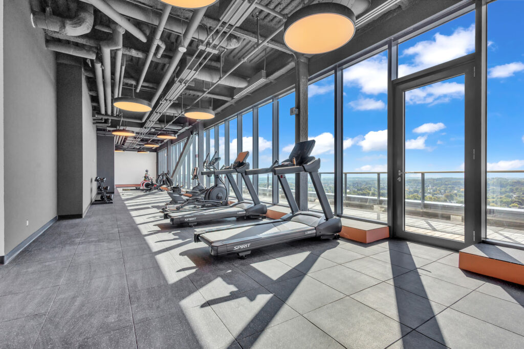 A gym featuring treadmills and large windows with a view of the city skyline.