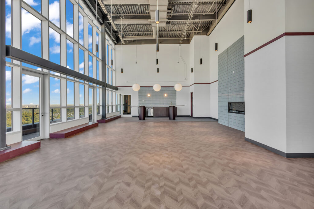 A spacious atrium with tall glass walls, allowing natural light to fill the area, surrounded by greenery and seating.