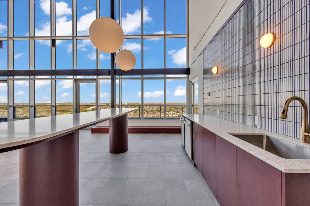 A modern kitchen with large windows showcasing a city skyline and waterfront view.