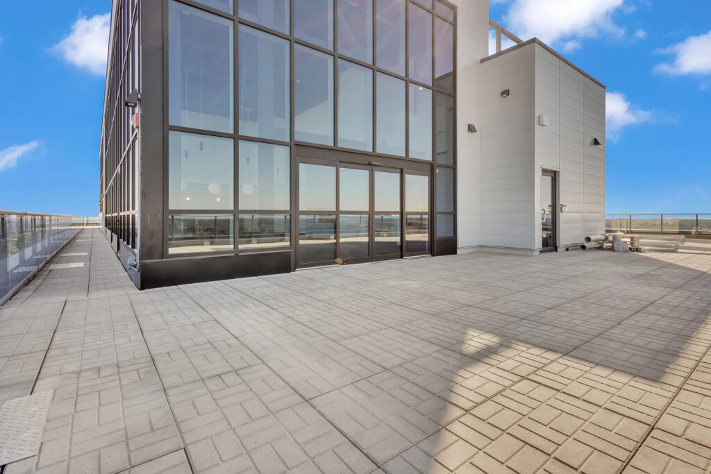 Rooftop deck of a New York City apartment with city skyline views, lounge chairs, and potted plants.