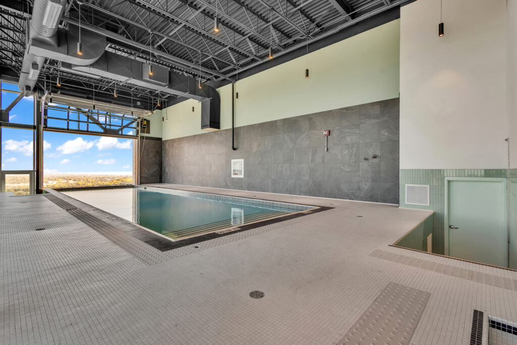 Indoor pool with clear water, surrounded by large windows offering a view of the outdoors.