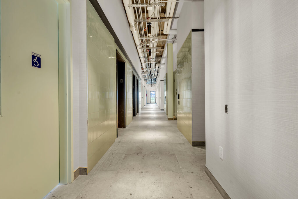 A long hallway featuring a white wall and a single door at the end.