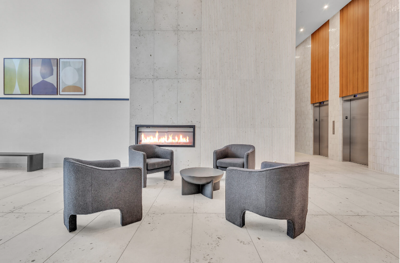 A modern lobby featuring comfortable chairs and a cozy fireplace, creating a welcoming atmosphere.